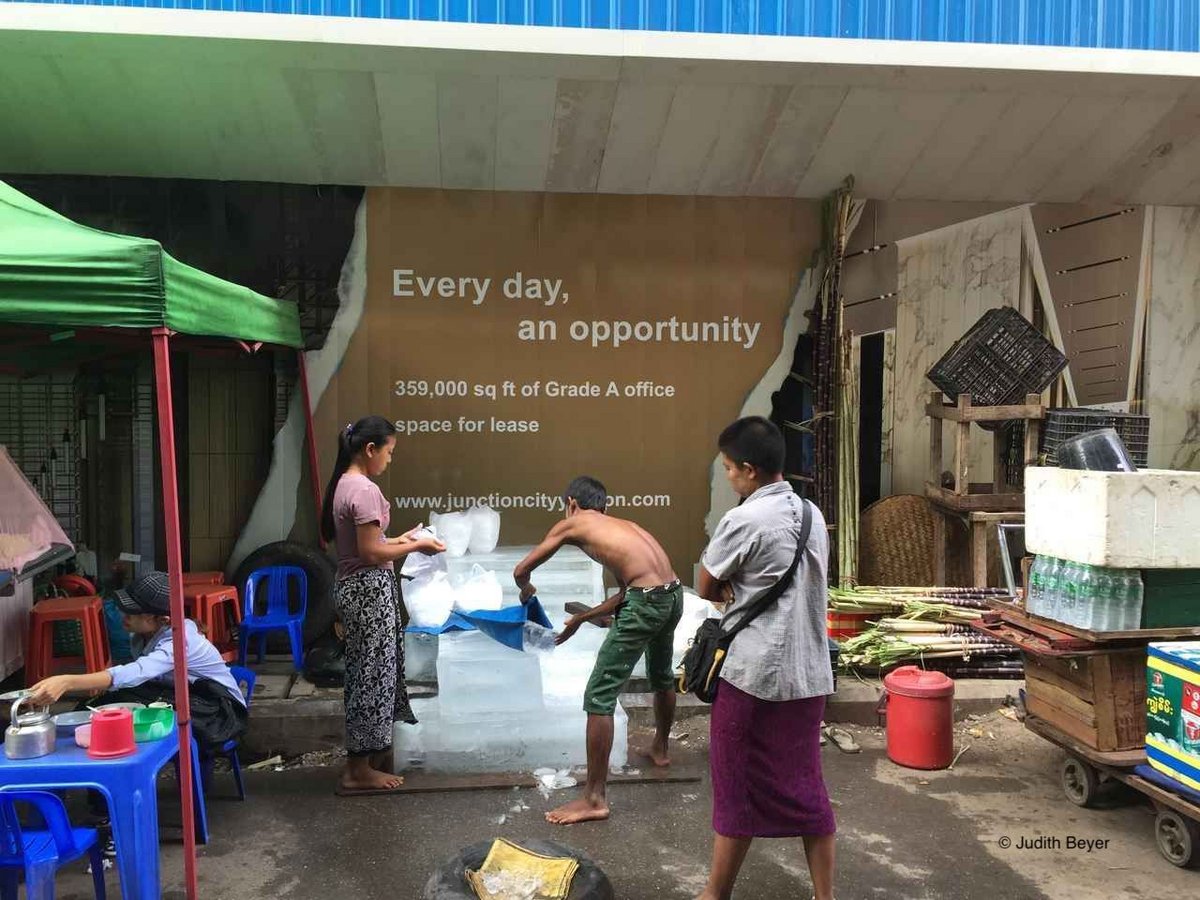 Street market in Myanma. On the wall is the slogan "Everyday. An oppertunity" printed